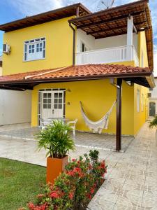 una casa amarilla con una hamaca delante en Kalug - Guest House com 3 quartos em Condomínio na Praia dos Milionários, en Ilhéus