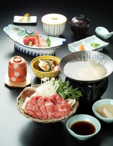 einen Tisch mit Schalen und Teller mit Lebensmitteln darauf in der Unterkunft Plaza Inn Mizusawa in Oshu