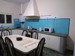 a kitchen with a table with chairs and a microwave at Casa céntrica El Rosal (cabaña) in San Rafael +4 photos