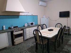 a kitchen with a table with chairs and a stove and refrigerator at Casa céntrica El Rosal (cabaña) in San Rafael