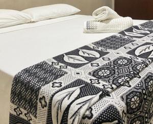 a bed with a black and white quilt on it at Casa em Paraty, piscina com vista para o mar in Paraty