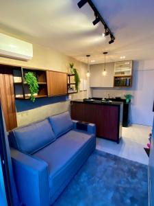uma sala de estar com um sofá azul e uma cozinha em COMPACT FLAT TAMBAU LUXO - Aptº 504 em João Pessoa