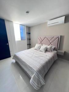 um quarto com uma cama grande com lençóis brancos e almofadas em Encanto urbano con la mejor vista y ubicación ! em Cúcuta