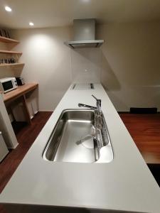 a kitchen with a sink in a white counter top at Aki's Apartments Madarao in Iiyama