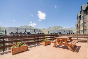 une table de pique-nique et deux plantes en pot sur un balcon dans l'établissement Snow y Bike Formigal, à Formigal