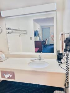 ein Badezimmer mit einem Waschbecken und einem großen Spiegel in der Unterkunft Ashley inn in Crossett