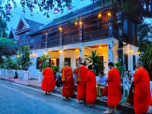 a group of people in red robes standing in front of a building at Lotus Corner - Vegan & Plant Based B&B in Luang Prabang