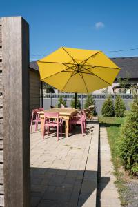 żółty parasol na patio ze stołem i krzesłami w obiekcie The Darcie House - cozy, pet-friendly home in PEC w mieście Picton