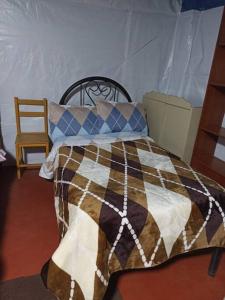 a bed with a blanket and a chair in a room at Posada Shumac Ñahui baño privado y ducha caliente in Huaraz