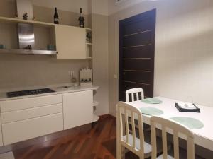 een keuken met witte kasten en een tafel en stoelen bij Dimora Shimbalaie in Bari