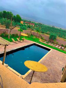 una piscina con una mesa y una sombrilla amarilla en Bienvenue à la Villa Luxe de 3 Suites pour Location Journée !, en Marrakech