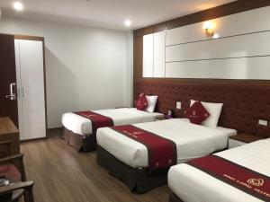 a hotel room with three beds with red pillows at Bình Long II Hotel in Lai Châu