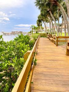 a wooden boardwalk leading to a beach with palm trees at A Cozy Space Coast Retreat in Titusville