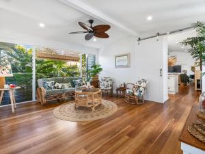a living room with a ceiling fan and a table at Kia Orana Island Home with Pool in Casuarina