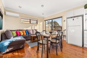 a kitchen and living room with a table and a couch at Orana by Experience Jervis Bay in Vincentia