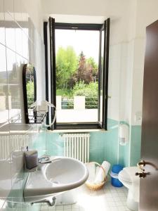 łazienka z umywalką, toaletą i oknem w obiekcie Hotel Villa San Fedele w mieście San Fedele Intelvi