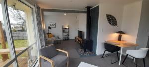 a living room with a table and a chair and a room with a television at River and Ridge Getaway in Turangi