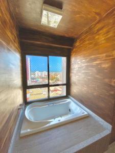 a bath tub in a room with a window at DUPLEX com Hidromassagem total de 02 QUARTOS e Vista MAR in Aracaju