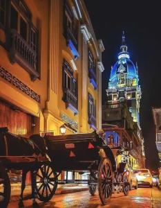 uma carruagem puxada por cavalos numa rua da cidade à noite em Catedral em Cartagena das Índias