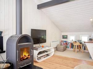 a living room with a fireplace and a tv at Holiday home Nexø X in Vester Sømarken