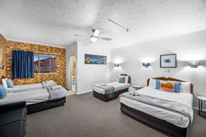 um quarto de hotel com duas camas e um sofá em Airport Clayfield Motel em Brisbane