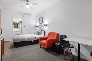 Airport Clayfield Motel في بريزبين: غرفة نوم بسرير وكرسي وطاولة