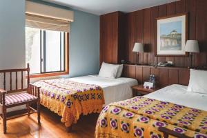 una habitación de hotel con 2 camas y una silla en Hotel Victoria, en Cuenca
