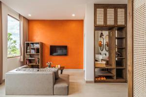 a living room with an orange accent wall at Miền Sương Khói - Home & Café in Khu Chi Lăng