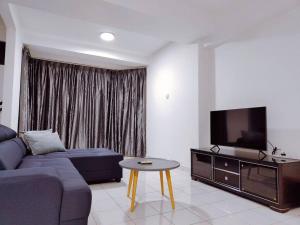 uma sala de estar com um sofá, uma televisão e uma mesa em Fahrenheit Pavilion By Cally Stay em Kuala Lumpur