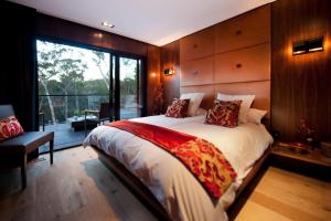 a bedroom with a large bed and a balcony at Harmony in Hepburn Springs