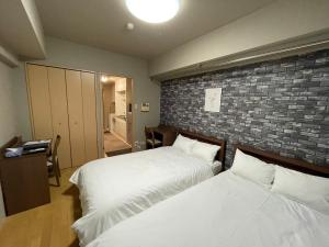 a bedroom with two beds and a brick wall at マルチステイ大阪心斎橋 in Osaka