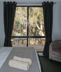 a bedroom with a large window with two towels on a bed at Deni Golf Resort in Deniliquin