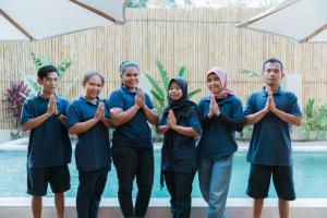 a group of people performing aorative yoga pose in front of a pool at The Gili Beach Resort in Gili Trawangan