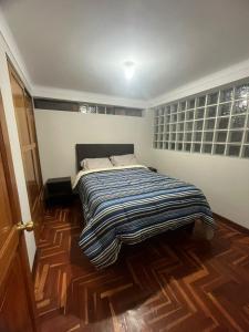 een bed met een gestreepte deken in een kamer bij Temporary departament in Cuzco