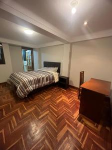 een slaapkamer met een bed en een houten vloer bij Temporary departament in Cuzco