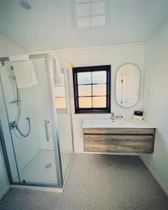 a bathroom with a sink and a shower with a mirror at Wylie Court Motor Lodge in Rotorua