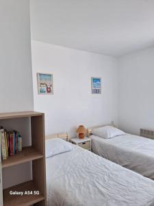 um quarto com duas camas e uma estante de livros em Appartement Chez A.S.Y. em Guérande
