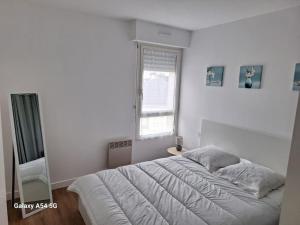 um quarto branco com uma cama grande e uma janela em Appartement Chez A.S.Y. em Guérande