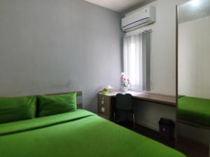 a bedroom with a green bed and a window at Barata Hotel Near Bandara Soekarno Hatta in Teko