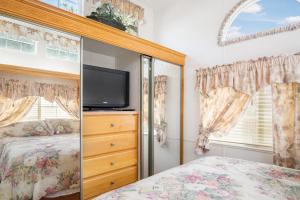a bedroom with a bed and a flat screen tv at River Run Park Model Cabin on Guadalupe in Kerrville