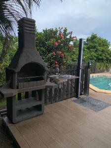 - une cheminée extérieure installée à côté d'une piscine dans l'établissement Héritage créole 4 - Mazurka, à Sainte-Luce