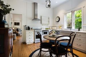 a kitchen with white cabinets and a table and chairs at Illoura in Hepburn Springs