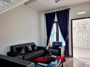 a living room with two black couches and a large window at Wafaby Guest House in Payakumbuh +27 photos