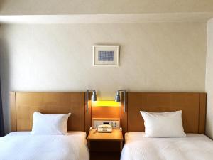 two beds sitting next to each other in a room at Valie Hotel Hiroshima in Hiroshima