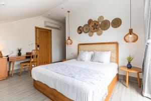 Schlafzimmer mit einem Bett, einem Tisch und einem Schreibtisch in der Unterkunft The Watermark Beachside Hotel in Hoi An