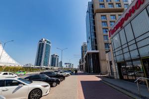 Una fila de autos estacionados en una calle en una ciudad en Raisson Ahotel F107, en Astana