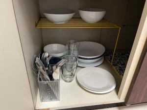 a cupboard filled with plates and bowls and utensils at マルチステイ大阪天神橋 in Osaka