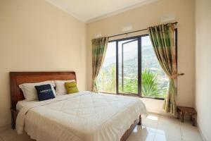 1 dormitorio con cama y ventana grande en Urbanview Resort Syariah Khansa Cisarua Puncak by RedDoorz en Tagalbato