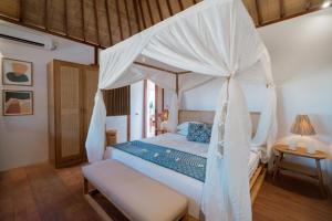 a bedroom with a bed with a canopy at The Gili Beach Resort in Gili Trawangan