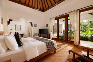 1 dormitorio con 1 cama blanca grande y TV en Puri Tempo Doeloe Boutique Hotel en Sanur